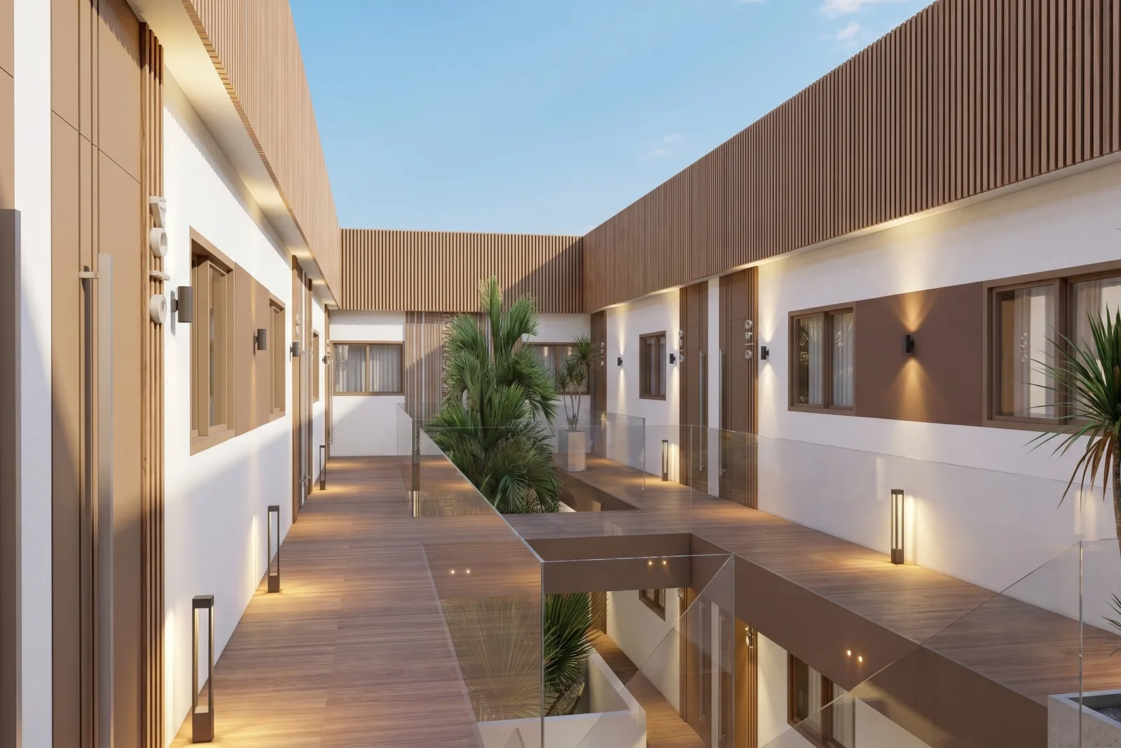 Nasłoneczniony widok wzdłuż ciągu komunikacyjnego patio Thalassa Living, z drewnianym tarasem, szklanymi balustradami i palmami rosnącymi w jego centrum.