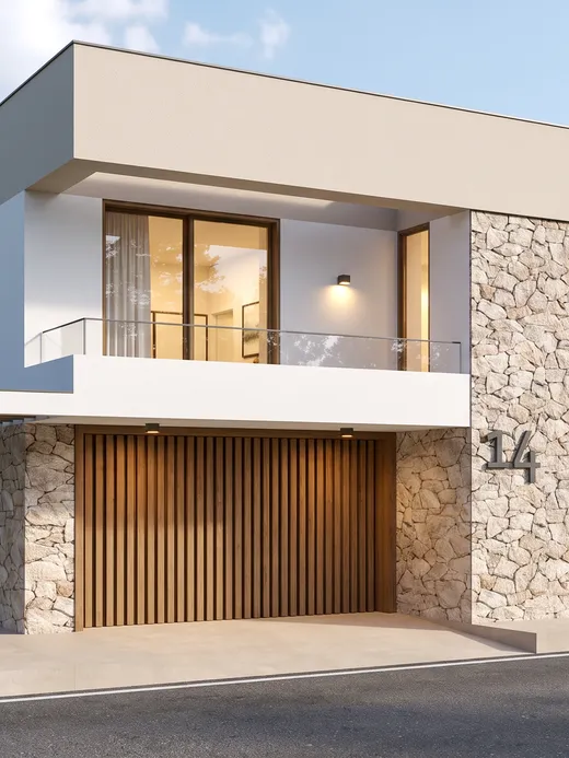 Front facade of Horizonte villa with a split-face stone corner, a timber-slat garage door, and a covered balcony over the entrance, set against pine and birch trees.