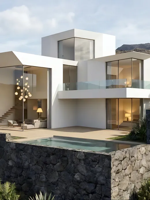 Clifftop white villa with cantilevered volumes overlooking the ocean horizon, edged by a rugged volcanic stone retaining wall and desert landscaping.