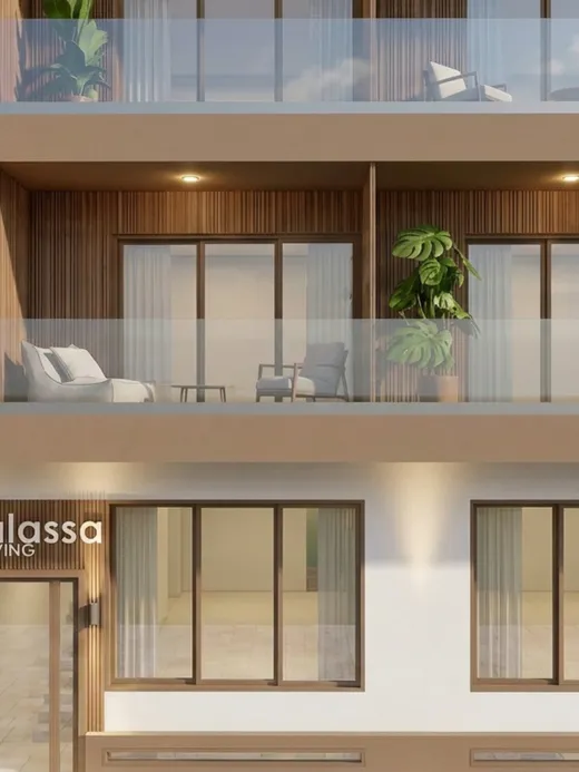 Close-up of Thalassa Living's timber-clad balconies and ground-floor lobby entrance with the building's illuminated signage.