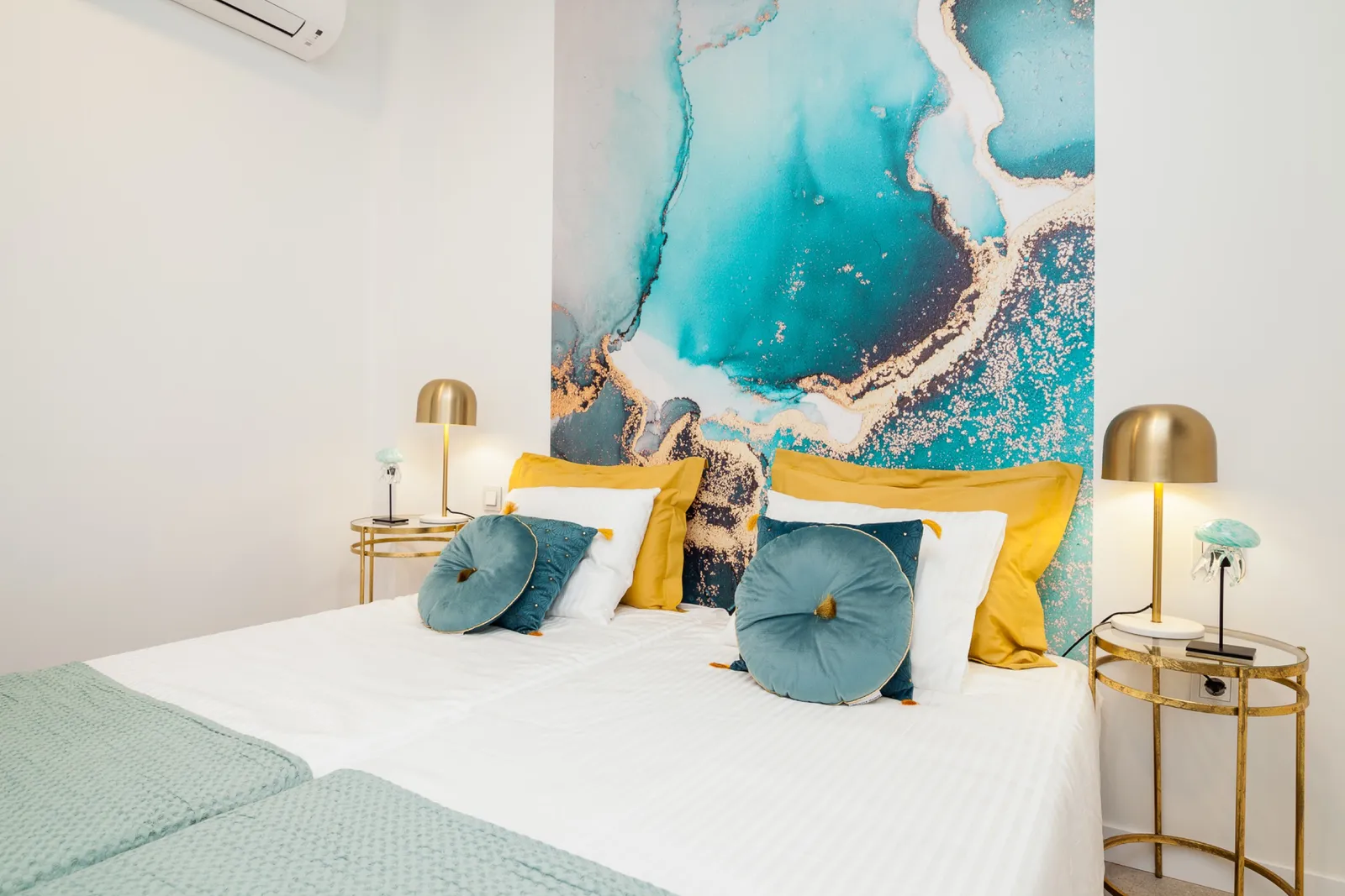 Bedroom with an emerald velvet bed and an oversized red-and-green fluid-art mural filling the headboard wall, with brass side tables.
