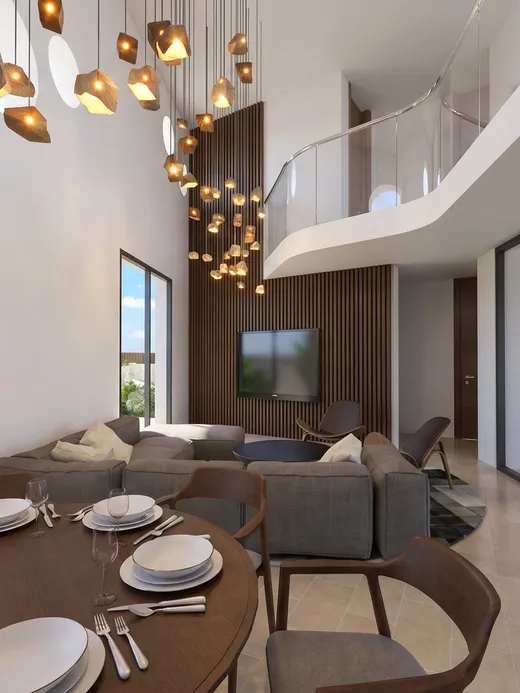 Double-height dining and living area with a sculptural hanging pendant light installation and a mezzanine walkway above.