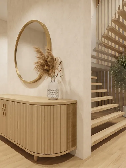 Entry hall with a round brass-framed mirror, a curved oak console table, and a floating timber staircase rising beside a glazed stairwell.