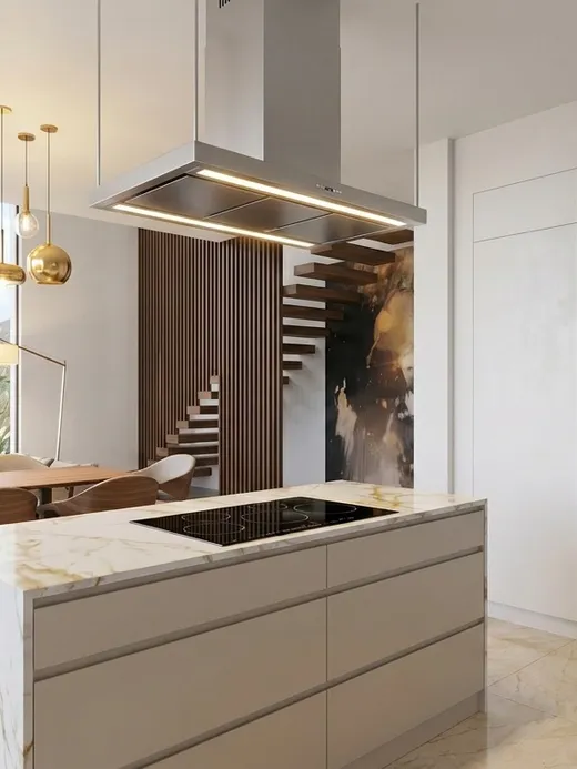 Open kitchen with a marble-topped island and integrated built-in ovens, framed by a mountain view through floor-to-ceiling glass.