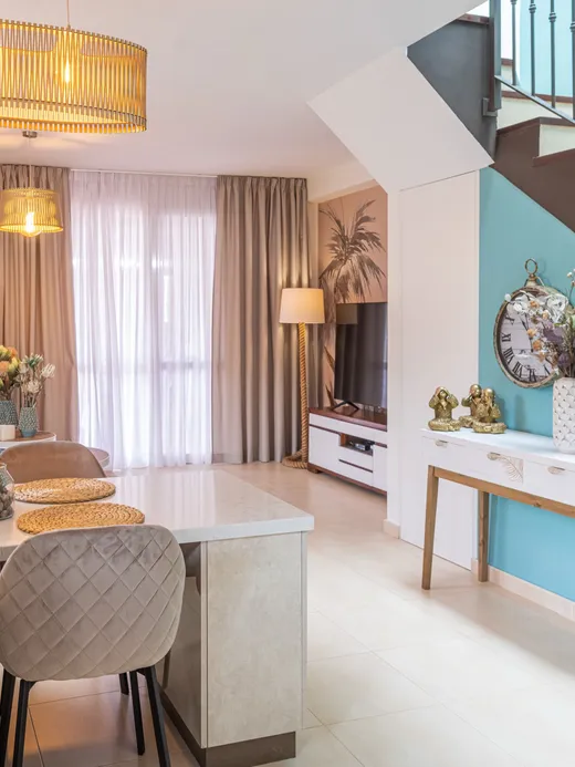 Open-plan living space with a turquoise stair accent wall, a tropical mural and a blue sofa beside the staircase.